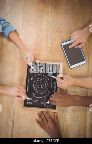 Overhead view of cropped hands writing business terms on slate with person using digital tablet Stock Photo