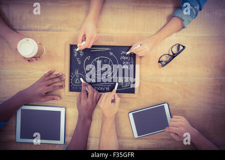 Overhead view of cropped hands writing business terms on slate with person touching digital tablet Stock Photo