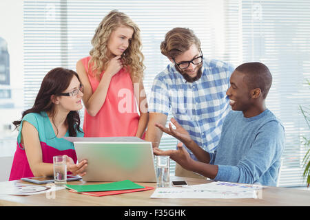 Man gesturing in front of coworkers in creative office Stock Photo
