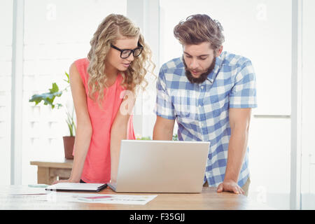 Man using laptop while discussing with woman at desk Stock Photo