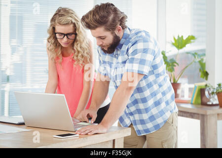 Man discussing with woman while using laptop at desk Stock Photo