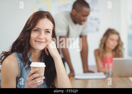 Thoughtful woman holding coffee cup while sitting at desk Stock Photo
