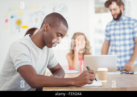 Man writing on paper while sitting at desk Stock Photo
