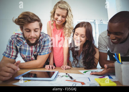 Smiling business team using digital tablet at desk Stock Photo