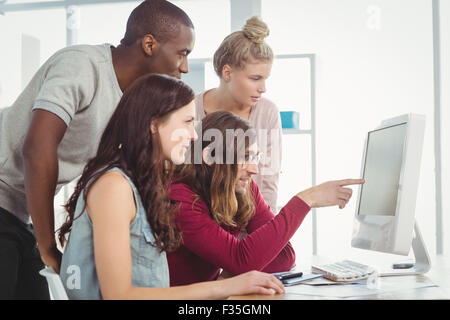 Man pointing at computer while working with coworkers in creative office Stock Photo