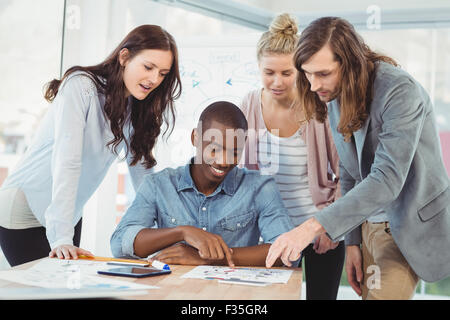 Smiling man pointing at diagram while discussing at desk Stock Photo