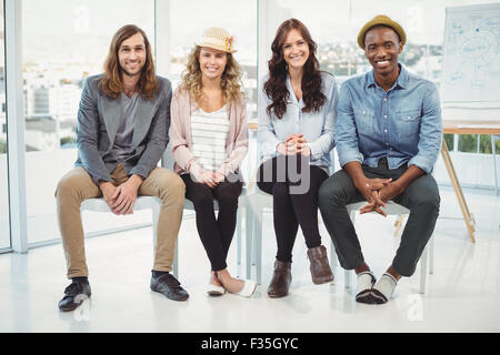 Full length portrait of smiling business people sitting on chair Stock Photo