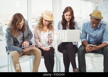 Business people using technology while sitting on chair Stock Photo