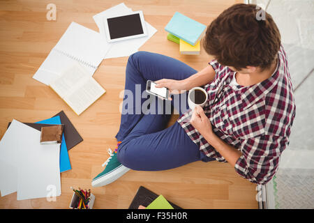 Hipster using smartphone while holding black coffee in office Stock Photo