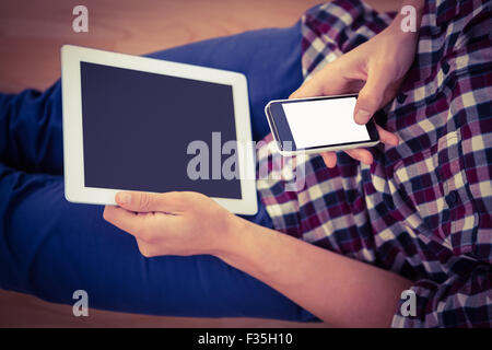 Man using smartphone while holding digital tablet Stock Photo