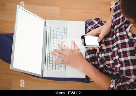 Hipster sitting with laptop using smartphone Stock Photo