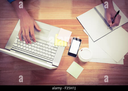 Businessman writing on spiral book using laptop Stock Photo