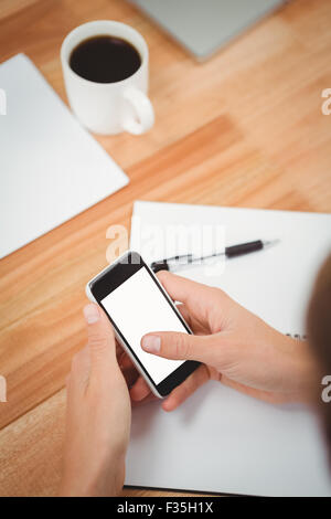 Businessman using smartphone at desk in office Stock Photo
