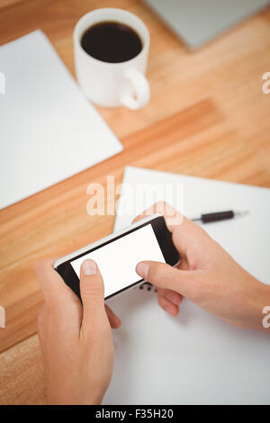 Man using smartphone at desk in office Stock Photo