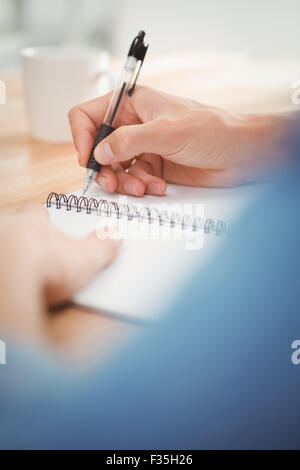 Businessman writing on spiral table at desk Stock Photo