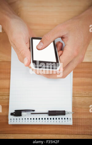 Man using smartphone with notepad on table in office Stock Photo