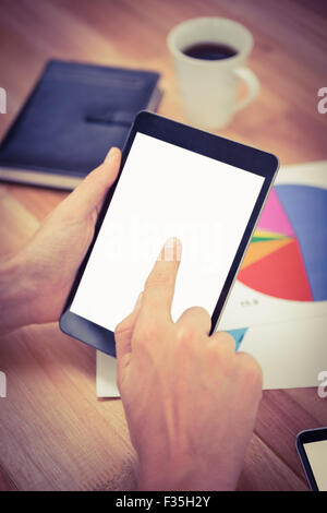 Man using digital tablet while documents and coffee on desk Stock Photo