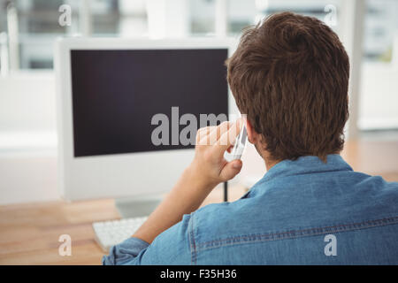 Hipster using mobile phone at desk in office Stock Photo