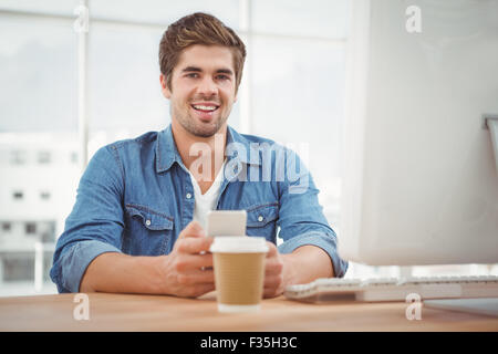 Happy businessman holding mobile phone at desk Stock Photo