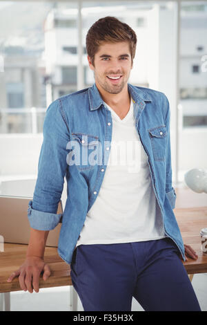 Happy hipster leaning on desk in office Stock Photo