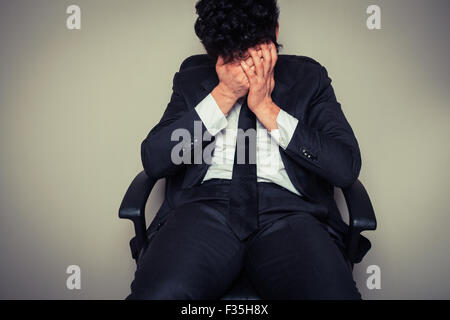 Sad and tired young businessman sitting in an office chair Stock Photo