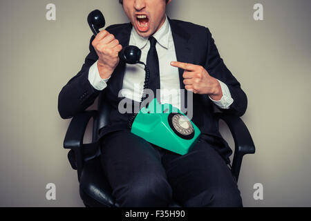 Angry businessman in office chair is on the phone Stock Photo