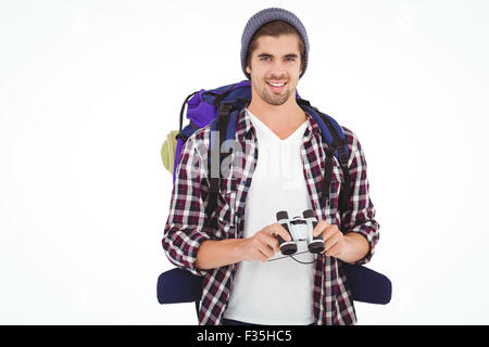 Happy hipster wearing backpack holding binoculars Stock Photo
