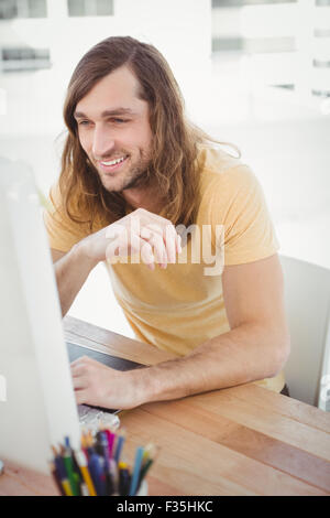 Hipster smiling while working on computer Stock Photo