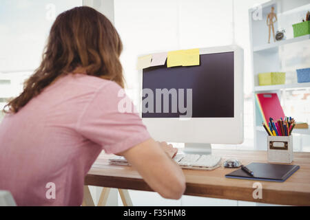 Rear view of hipster working on computer Stock Photo