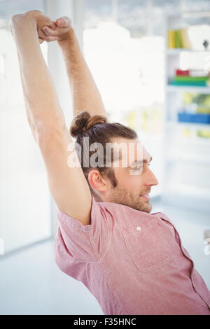 Businessman stretching in office Stock Photo