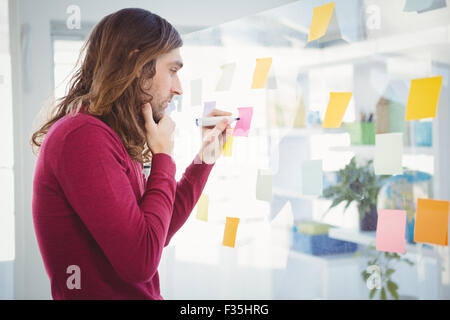 Thoughtful Hipster writing on sticky note Stock Photo