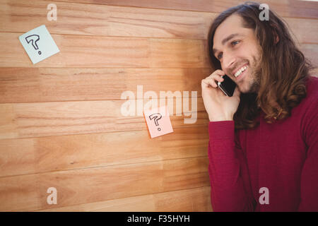 Happy man using mobile phone leaning on wooden wall Stock Photo