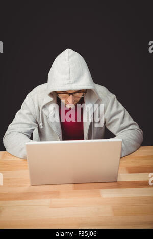 Man with hooded shirt working on laptop Stock Photo