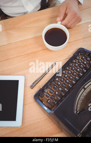 Businessman holding black coffee at desk in office Stock Photo