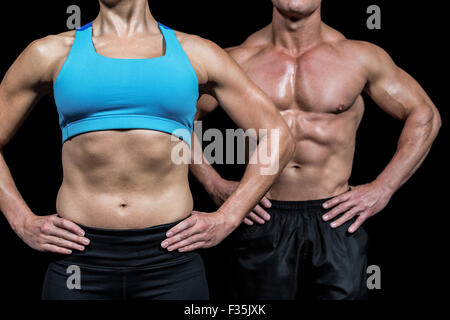 Midsection of muscular woman and man standing with hands on hip Stock Photo