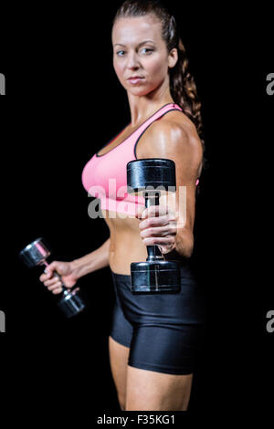 Portrait side view of woman exercising with dumbbells Stock Photo