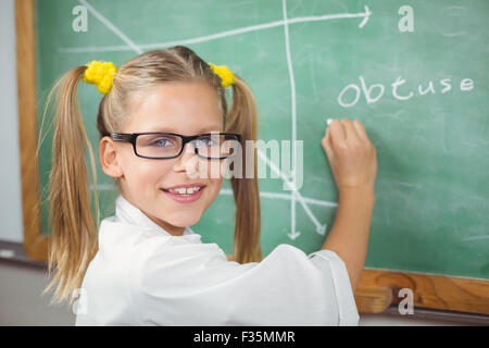 Cute pupil with lab coat writing on chalkboard Stock Photo