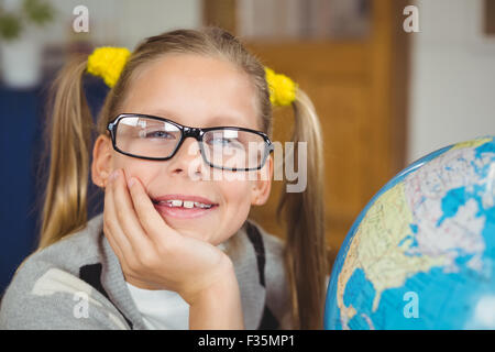 Cute pupil smiling next to globe in a classroom Stock Photo - Alamy