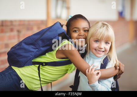 Cute pupils embracing at corridor Stock Photo