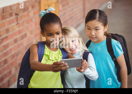 Cute pupils taking selfies at corridor Stock Photo