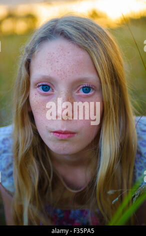 Portrait of an eight year old girl in a field on a summers evening Stock Photo