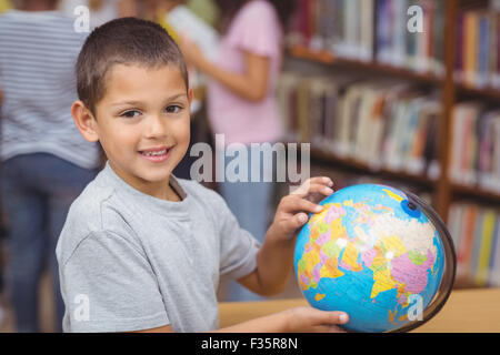 Pupil in library pointing to globe Stock Photo - Alamy