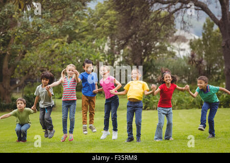 Cute pupils cheering on the grass outside Stock Photo