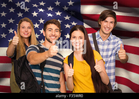 Composite image of happy students gesturing thumbs up at college corridor Stock Photo