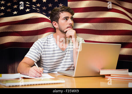Composite image of student studying in the library with laptop Stock Photo