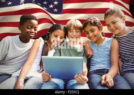 Composite image of happy children using digital tablet at park Stock Photo