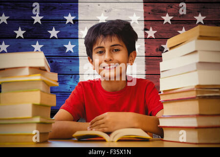 Composite image of portrait of boy reading book at desk Stock Photo