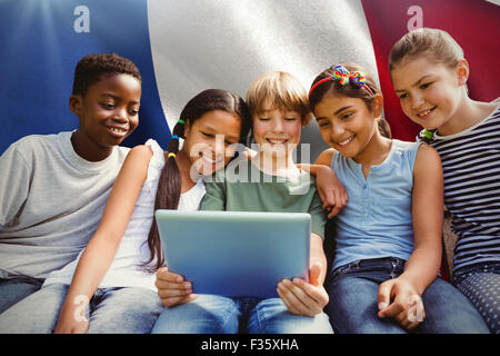 Composite image of happy children using digital tablet at park Stock Photo