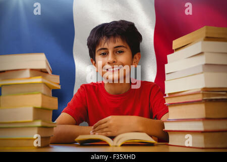 Composite image of portrait of boy reading book at desk Stock Photo