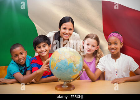 Composite image of cute pupils and teacher looking at globe in library Stock Photo